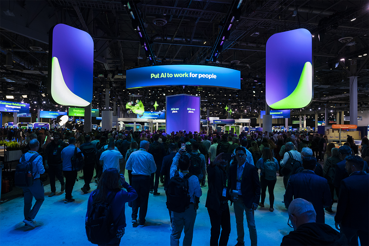 Crowds on the ServiceNow Knowledge 2026 expo floor beneath a blue and green event banner.