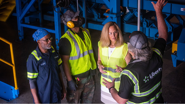 Workers in safety vests and ear protection converse on the floor of the Liberty Tire Recycling facility in Sanford, North Carolina.