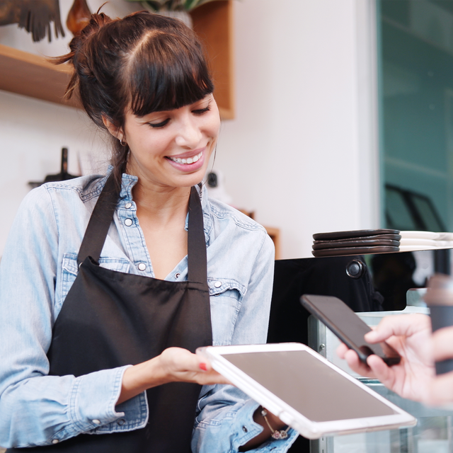 Smiling woman holding a tablet for a customer to scan with his phone