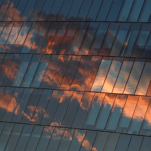 Architecture of glass building with reflection of sky sunset