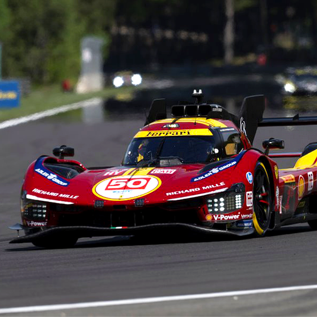 A red Ferrari car driving down a racetrack
