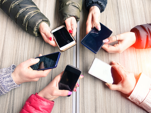 Arms and hands holding five phones in a circle