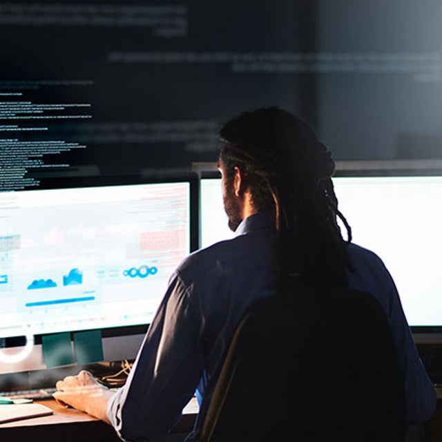 Back of man sitting in front of double-screen monitor showing dashboard