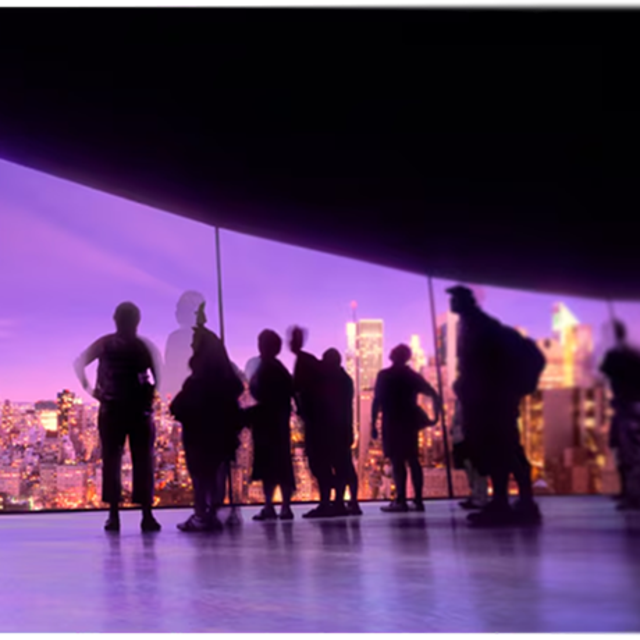 Group of people looking out on a city through floor-to-ceiling windows 