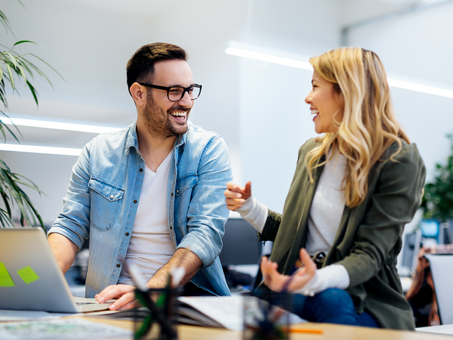 Man and a woman collaborating in front of a laptop in an office
