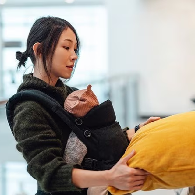 Female holding baby in a sling shopping