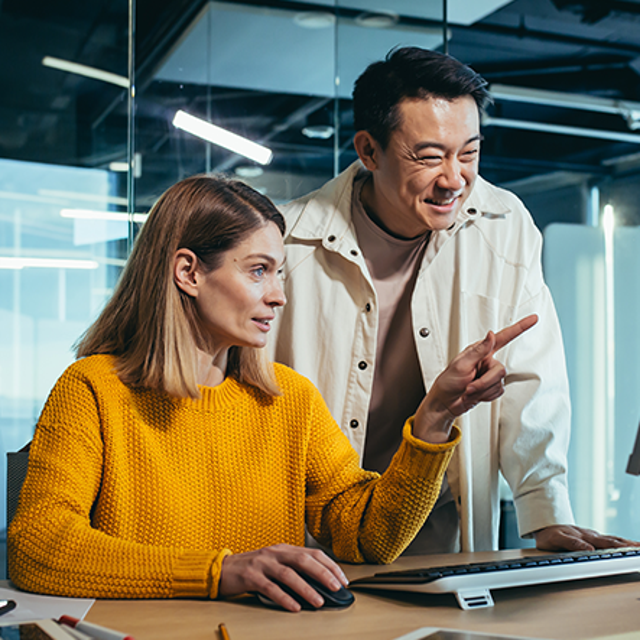 Man smiling at a laptop while jotting notes