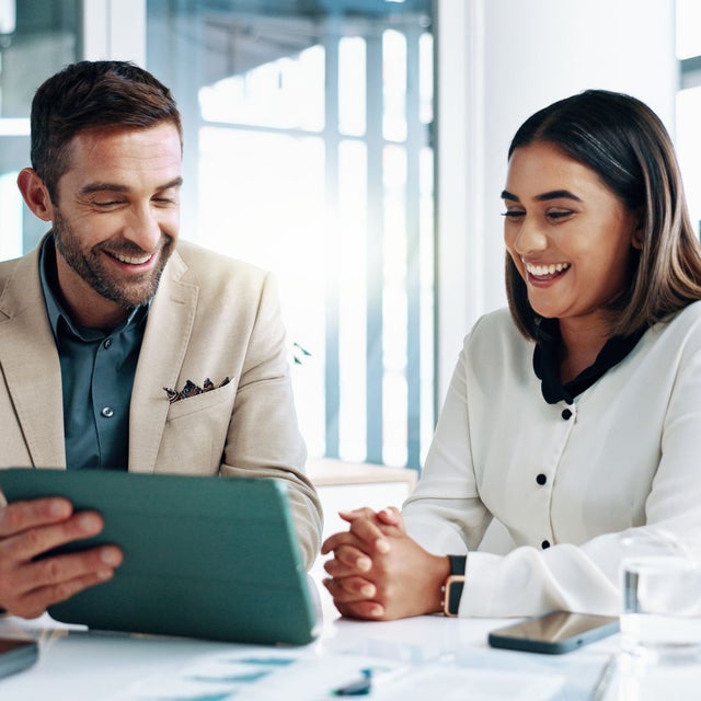 2 happy workers collaborating over a tablet in a bright office
