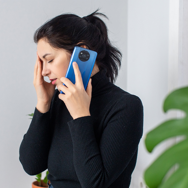 Woman looking frustrated with a phone to her ear and her hand on her forehead