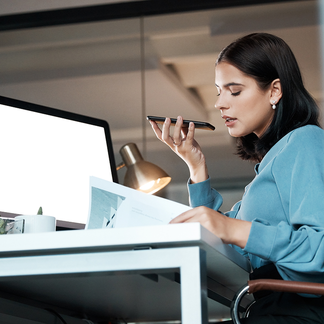 Woman sitting at an office desk and speaking into a phone
