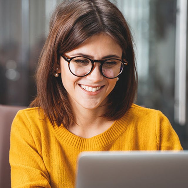 AI potential: smiling worker looking at her open laptop
