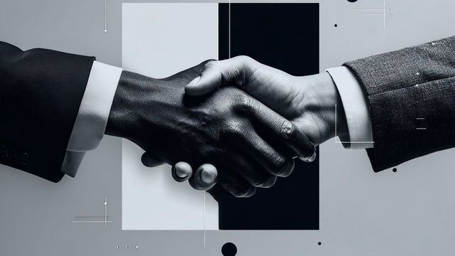 Two hands engaged in a handshake in front of a black and white square