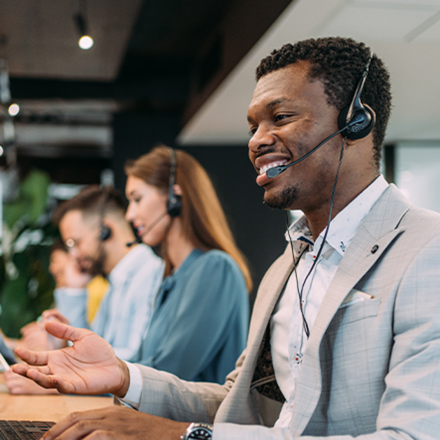 A line of customer service agents wearing headsets working in a contact center