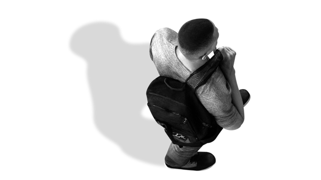 Male walking holding a backpack over shoulder