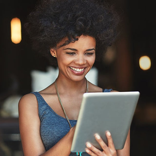 Woman smiling at tablet in her hands in a dimly lit building