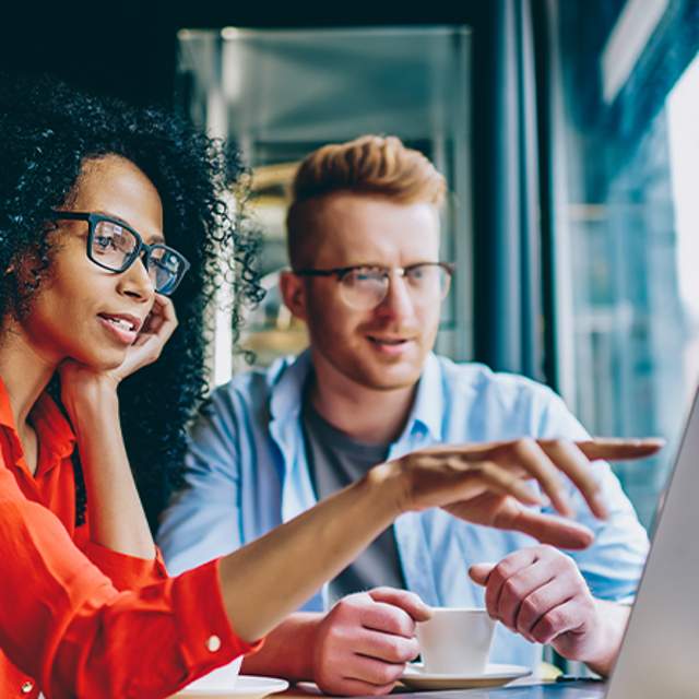 Two people in an office looking at a laptop