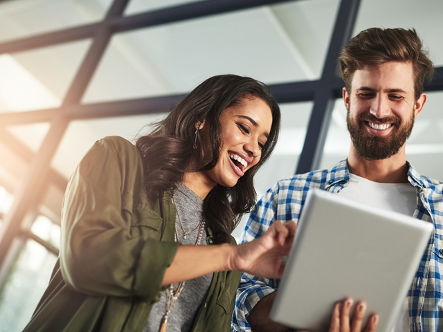 Two smiling workers looking at a tablet