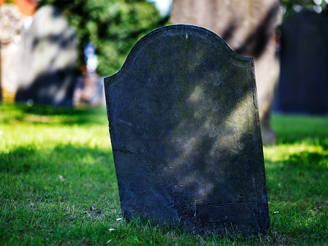 Dark, blank gravestone in grass