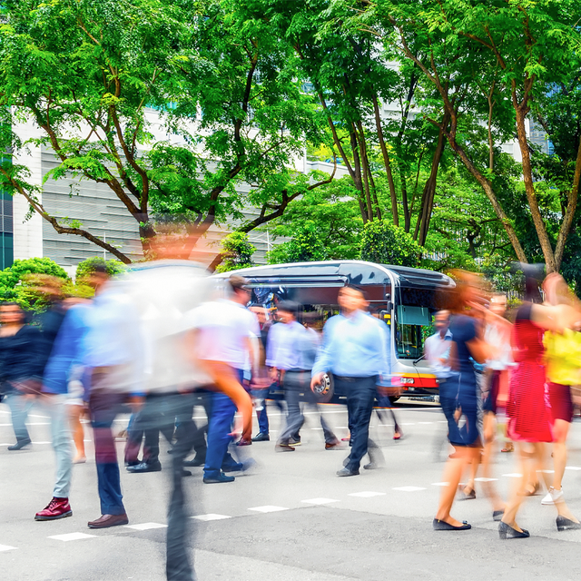 People walking across a street in Singapore with motion blur