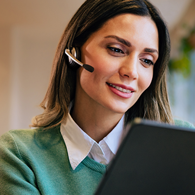 The future of CRM: woman wearing a headset smiling at a tablet in her hands