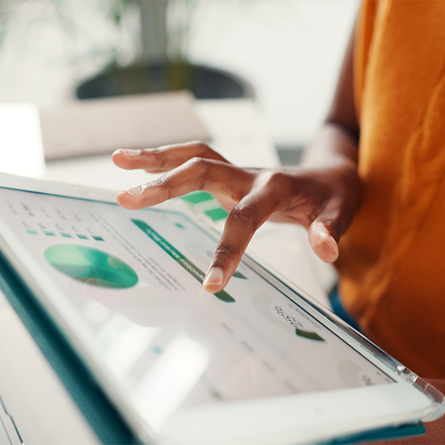 A hand on a tablet displaying graphs