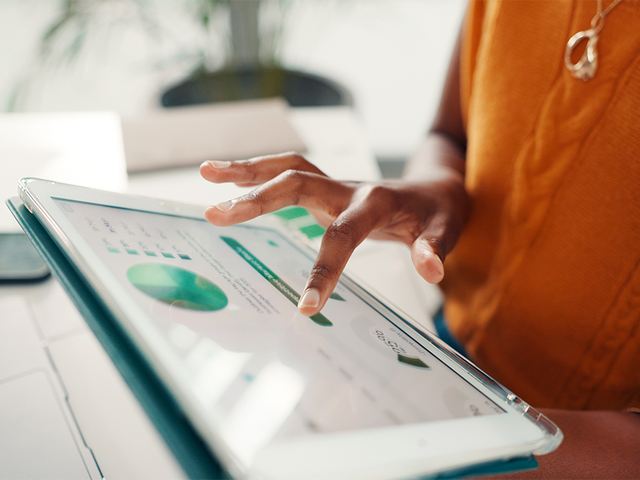 A hand on a tablet displaying graphs