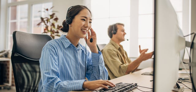 Woman sitting at desk in front of laptop on the phone