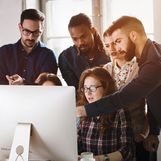 A group of people in an office looking at a computer screen