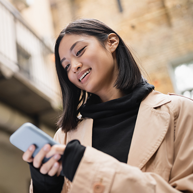 Young woman smiling at the phone in her hands