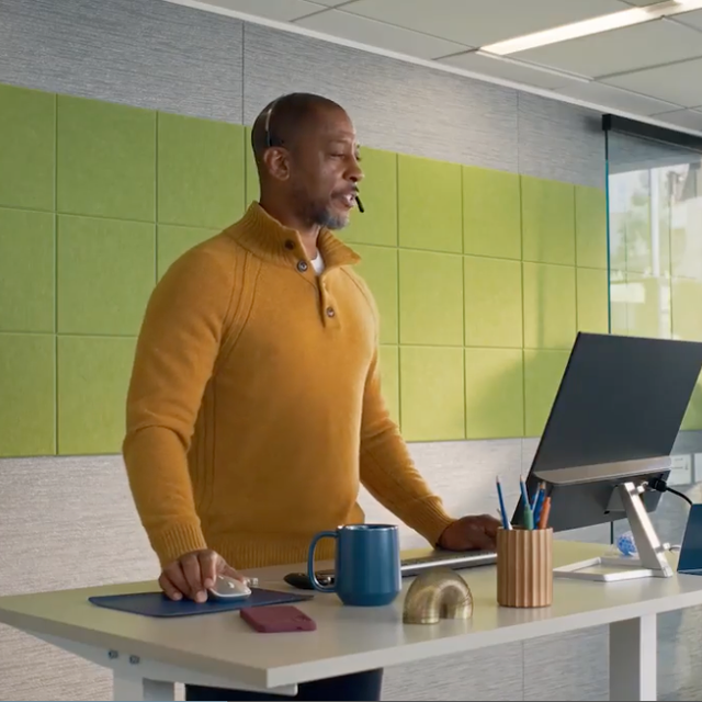 ServiceNow CRM character Jim wearing a headset at a stand-up desk