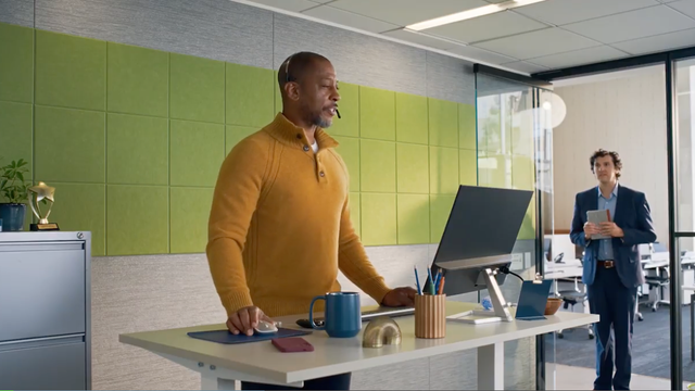 ServiceNow CRM character Jim wearing a headset at a stand-up desk