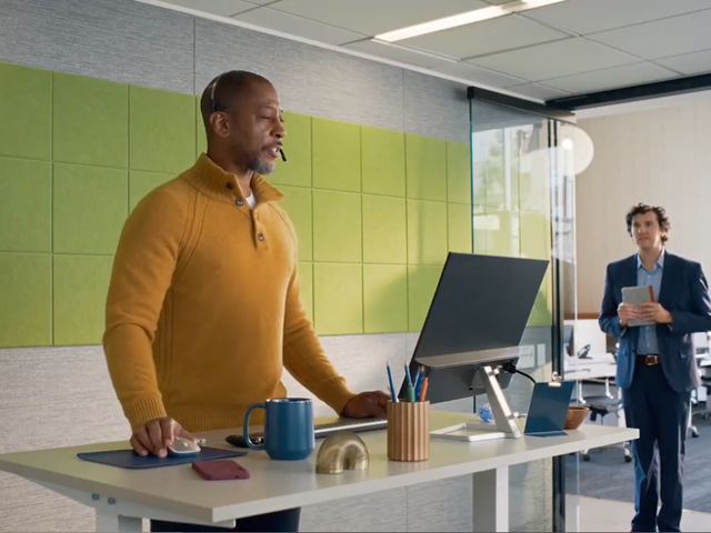 ServiceNow CRM character Jim wearing a headset at a stand-up desk