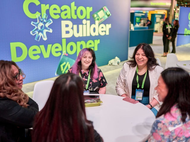 Five women gathered around a table at CreatorCon at ServiceNow Knowledge
