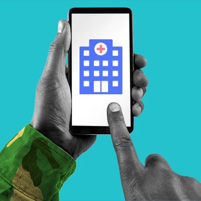Hand with a camouflaged sleeve holding a phone showing a picture of a hospital
