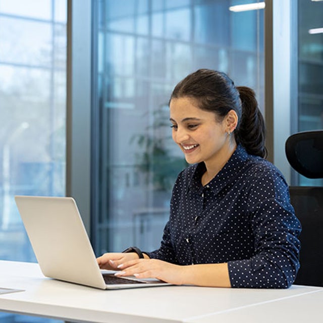 Demographic dividend: woman smiling at open laptop in an office