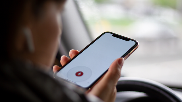 Woman using voice to text on a phone in the car