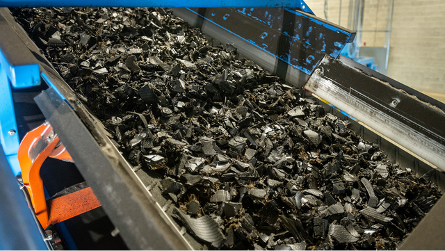 Close-up of shredded tire material moving along a conveyor belt at the recycling facility.