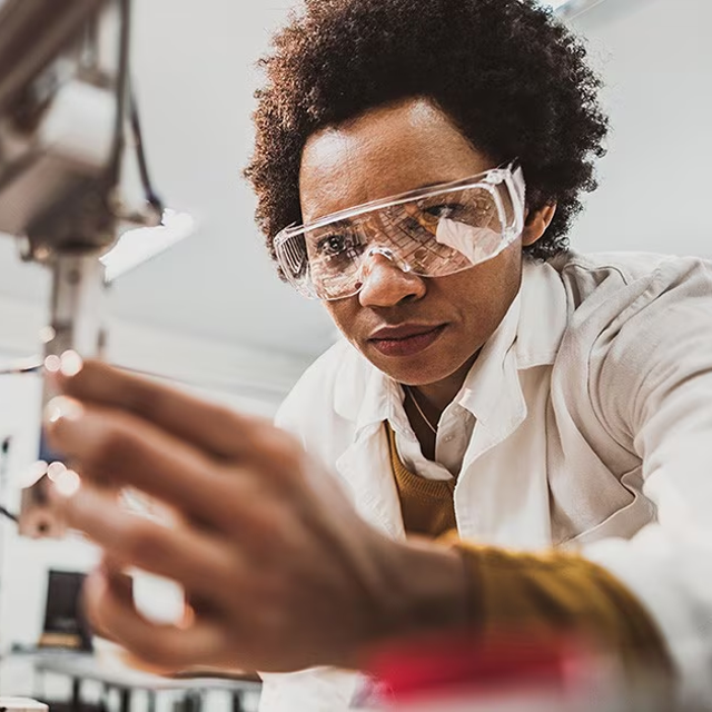 Female researcher wearing goggles and a lab coat working in a lab