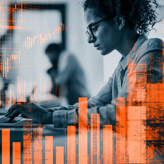 Woman in black and white working on a computer behind an overlay of orange graphs