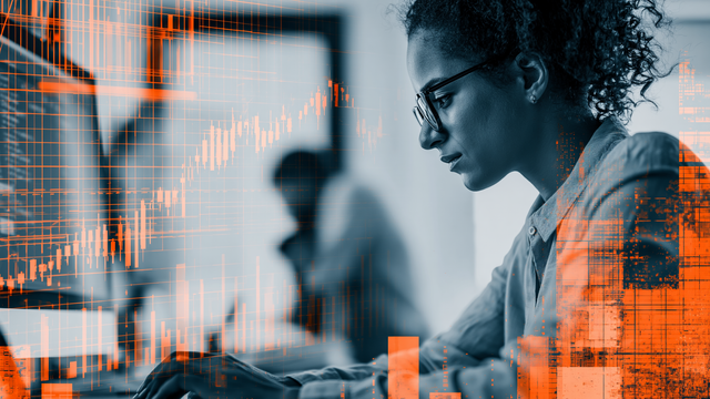 Woman in black and white working on a computer behind an overlay of orange graphs