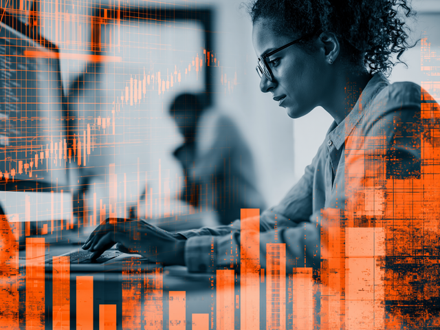 Woman in black and white working on a computer behind an overlay of orange graphs