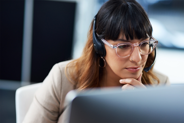 Business woman wearing a headset looking intently at her computer
