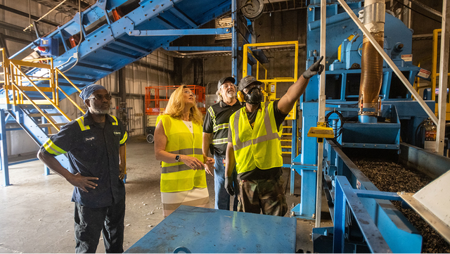Workers in safety vests inspect industrial machinery inside the Liberty Tire Recycling facility in Sanford, North Carolina.