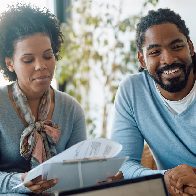 Two people smiling and talking to an insurance agent