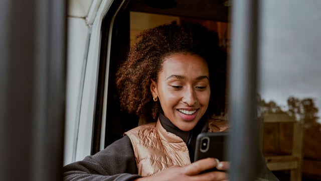 A woman in a stopped vehicle looking at a smartphone