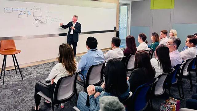 ServiceNow Chief Technology Officer Pat Casey writing on a whiteboard in front of a seated audience