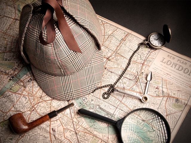 Detective hat, pipe, magnifying glass, and pocket watch on a London map