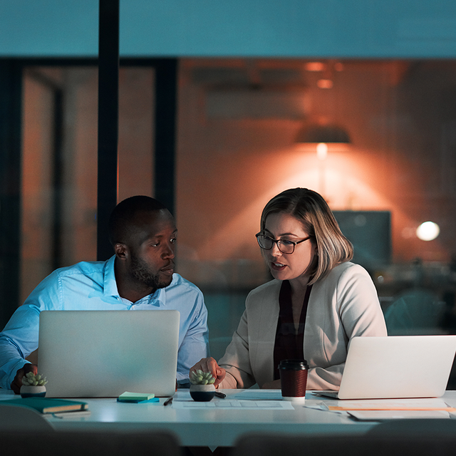 Two people working together with laptops in an office