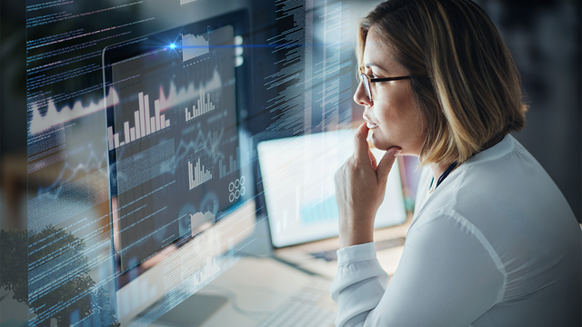 Woman at a desk staring at analytics on a computer screen
