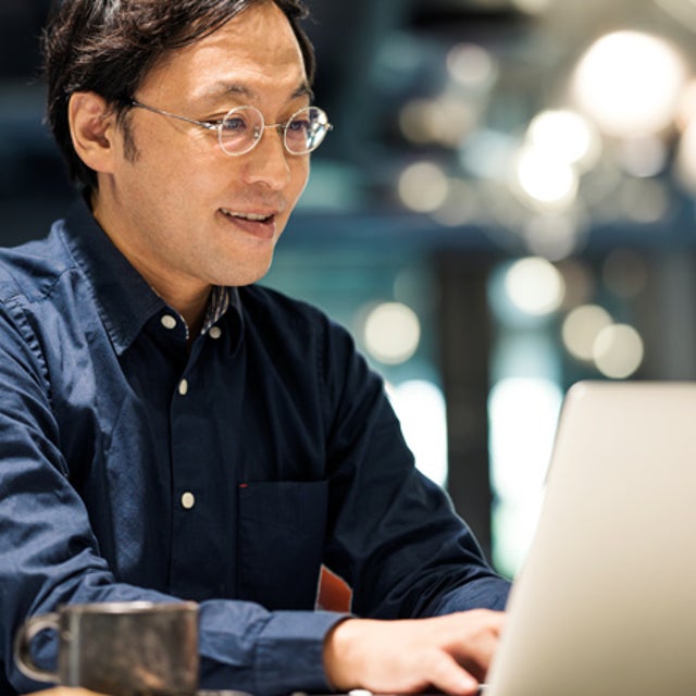 Man with glasses typing on a laptop